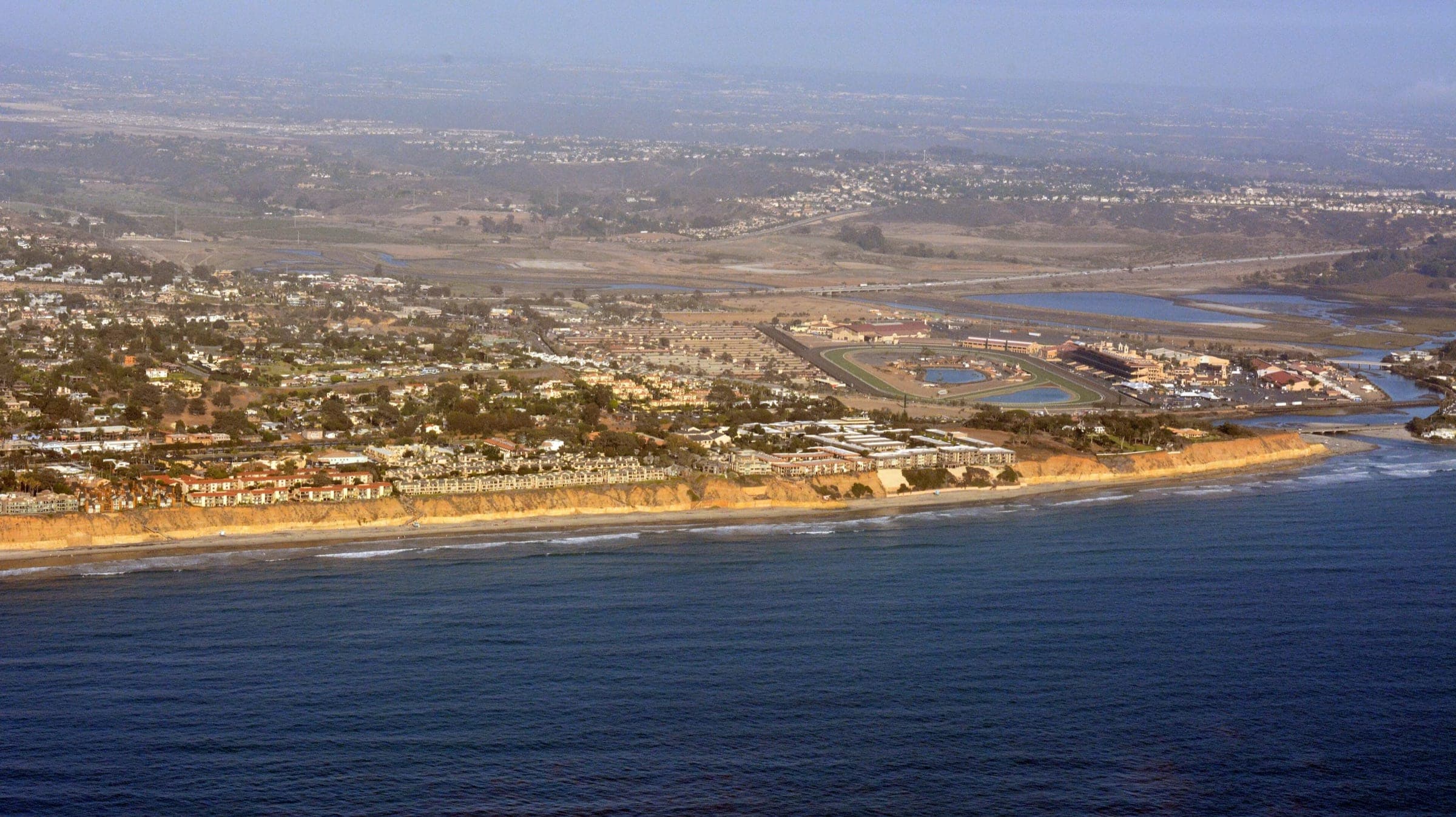 Aerial view of the coast at Del Mar and Solana Beach, with bluff-top homes, the fairgrounds racetrack and the San Dieguito Lagoon